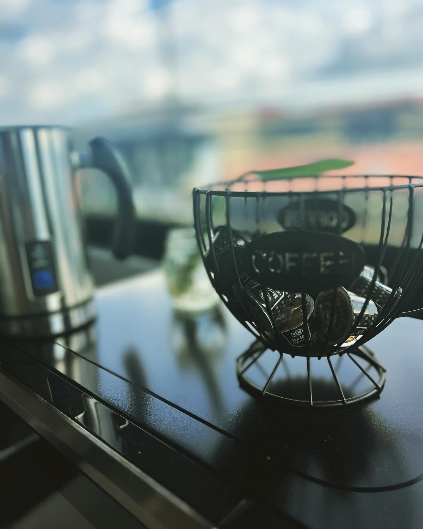 A kitchen counter with a coffee maker and a metal coffee basket.