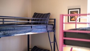 A bunk bed with a mattress and pillows, a framed picture on the wall, and a small table with a decorative item. - FunStation: 2800sqft Reno Getaway for All Ages (Sparks)