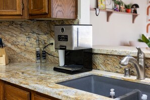 Eine Küche mit integrierter Kaffeemaschine, Granitarbeitsplatte, Edelstahlspüle und Holzausstattung.