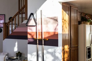 A staircase with a triangular warning sign, a kitchen with wooden cabinets, and a refrigerator. - FunStation: 2800sqft Reno Getaway for All Ages (Sparks)