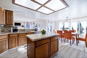 A modern kitchen with wooden cabinets, a granite countertop, and a large island. - FunStation: 2800sqft Reno Getaway for All Ages (Sparks)