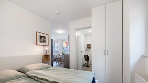 A bedroom with a bed, a wardrobe, a framed picture on the wall, and a view into the adjacent room. - Holiday Apartment 'Rieslingglück' with Wi-Fi (Trittenheim)