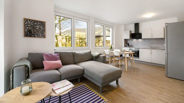 A modern kitchen with a grey refrigerator, white cabinets, and a dining area with a table and chairs. - Holiday Apartment 'Rieslingglück' with Wi-Fi (Trittenheim)