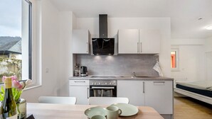 A modern kitchen with white cabinets, a built-in oven, and a large window. - Holiday Apartment 'Rieslingglück' with Wi-Fi (Trittenheim)