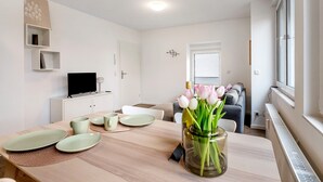 A modern living room with a dining table, a TV, a sofa, and a window with a view. - Holiday Apartment 'Rieslingglück' with Wi-Fi (Trittenheim)