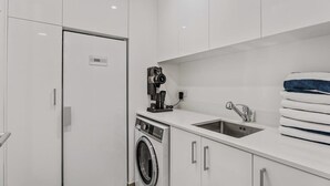 Eine moderne Küche mit eingebauter Waschmaschine, einem Spülbecken und einer Kamera auf der Arbeitsplatte.