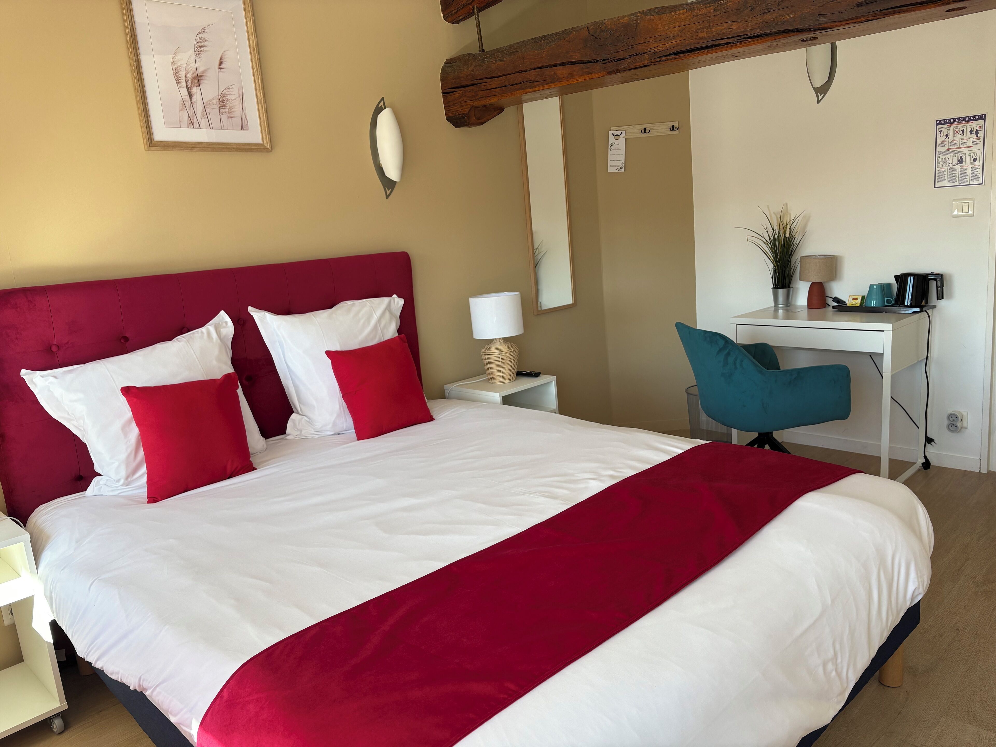 A hotel room with a large bed, a desk, and a chair.