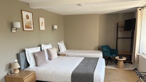 A hotel room with two beds, a desk, a chair, a TV, and artwork on the walls. - Comme chez soi (Jas)