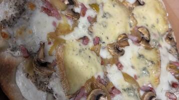 Pizza con queso, champiñones y jamón sobre un recipiente de cartón.