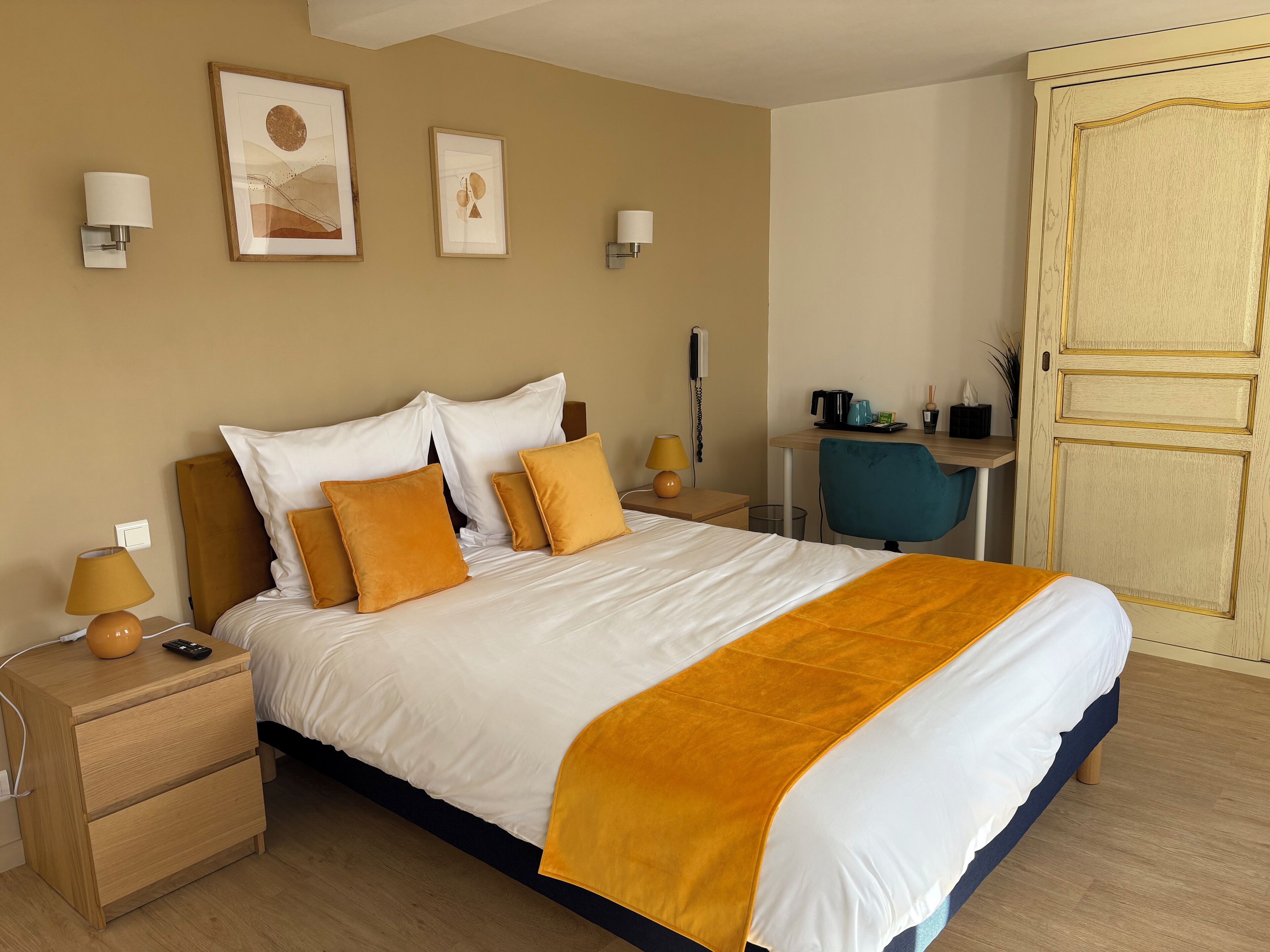 Siististi järjestetty hotellihuone, jossa on suuri sänky, yöpöydät, työpöytä ja tuoli.