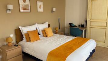 A neatly arranged hotel room with a large bed, bedside tables, a desk, and a chair.