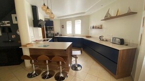 Una cocina moderna con una isla central, taburetes de bar y un horno empotrado.
