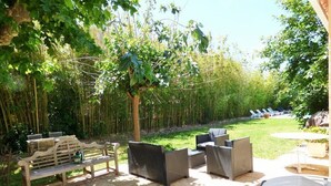 Un espacio de patio al aire libre con mobiliario de mimbre, un banco de madera y una mesa pequeña.