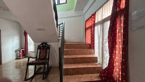 A staircase with red curtains, a wooden chair, and a tiled floor. - Hotel O Wisma Alam Syariah Near PLN GARDU INDUK MAMUJU (Mamuju)