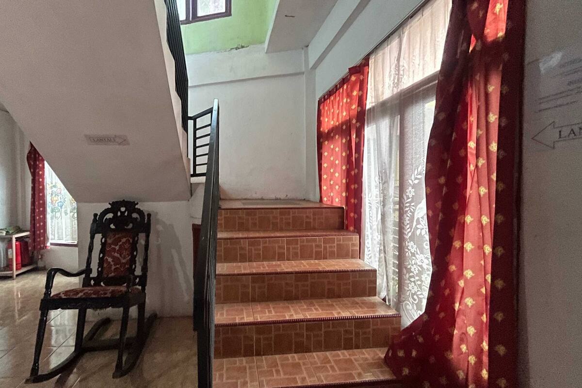 Una escalera con cortinas rojas, una silla de madera y un suelo de baldosas.