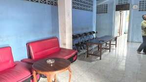 A waiting area with a red sofa, a wooden table with a ashtray, and a row of black chairs. - Hotel O Wisma Alam Syariah Near PLN GARDU INDUK MAMUJU (Mamuju)