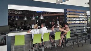 A bar area with a sign reading "CAYO Caribe" and several people seated at the bar.