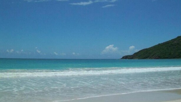 A beach with clear turquoise water and a sandy shore.