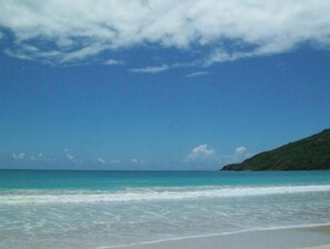 A beach with clear turquoise water and a sandy shore. - 1b/1b Beach house & steps from Trendy Loiza street! (San Juan)