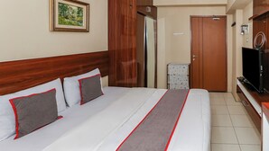 A hotel room with a large bed, a television, a wooden wardrobe, and a door. - Capital O 93371 Pelangi Residence 5  (South Tangerang)