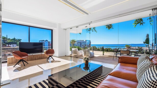 Un salón moderno con una mesa de centro de cristal, sofá de cuero y un televisor de pantalla plana.