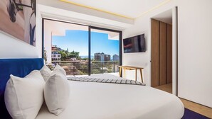 Un dormitorio moderno con una cama grande, una mesita y un televisor.