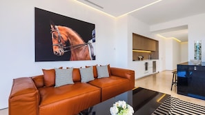 A modern living room with a leather sofa, a large painting, and a glass coffee table.