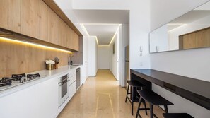 A modern kitchen with a central island, bar stools, and a long countertop.