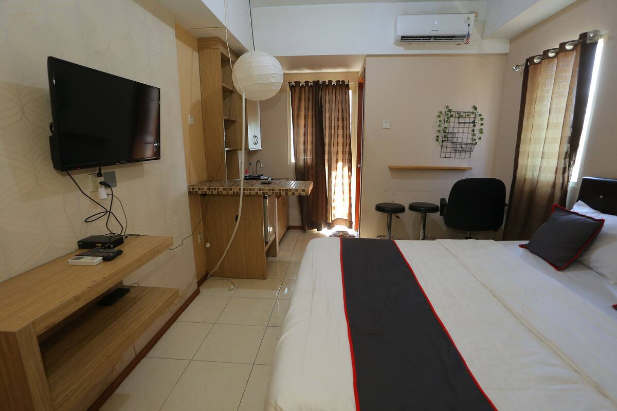 A hotel room with a bed, a TV, a desk, and a chair.