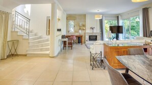 A spacious living area with a fireplace, a dining table, and a kitchen area with a TV.
