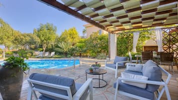 A poolside area with a covered patio, lounge chairs, and a dining table.