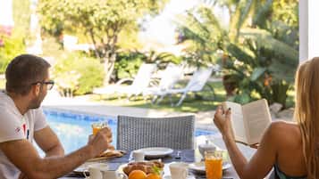 Una mesa de desayuno con alimentos, un libro y un vaso de jugo de naranja.