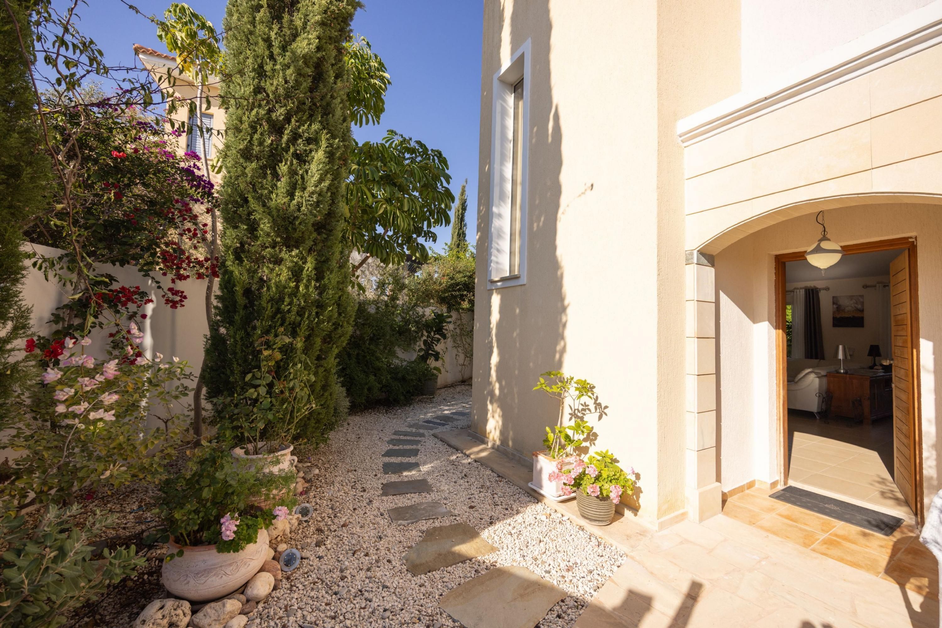 A narrow pathway leading to a building entrance with a door and a small porch area.