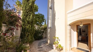 A narrow pathway leading to a building entrance with a door and a small porch area.
