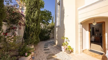 A narrow pathway leading to a building entrance with a door and a small porch area.