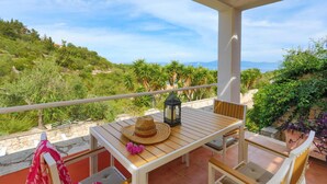 Ein Balkon mit Holztisch, Stühlen, einem Hut und einer Laterne.