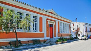 Ein Gebäude mit roter Tür, weißen Säulen, einer Bank und einem Baum davor.