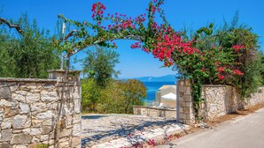 A stone-walled entrance with a view of the sea and mountains. - Beach House Sophia in Paxi (Paxos)