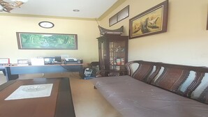 Un salon comprenant un canapé, une table basse, un bureau avec un ordinateur, une horloge et des œuvres d’art encadrées accrochées aux murs.