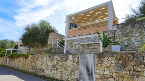 A modern building with a stone wall, a metal gate, and a pergola. - Villa Stelios in Paxi (Paxos)
