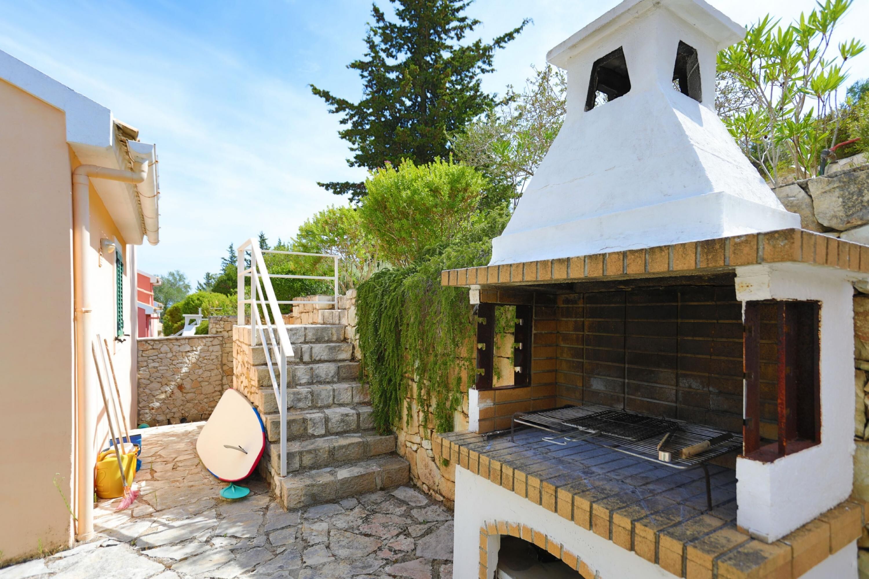 Uma área de churrasco ao ar livre com uma escadaria de pedra que leva a um edifício branco.