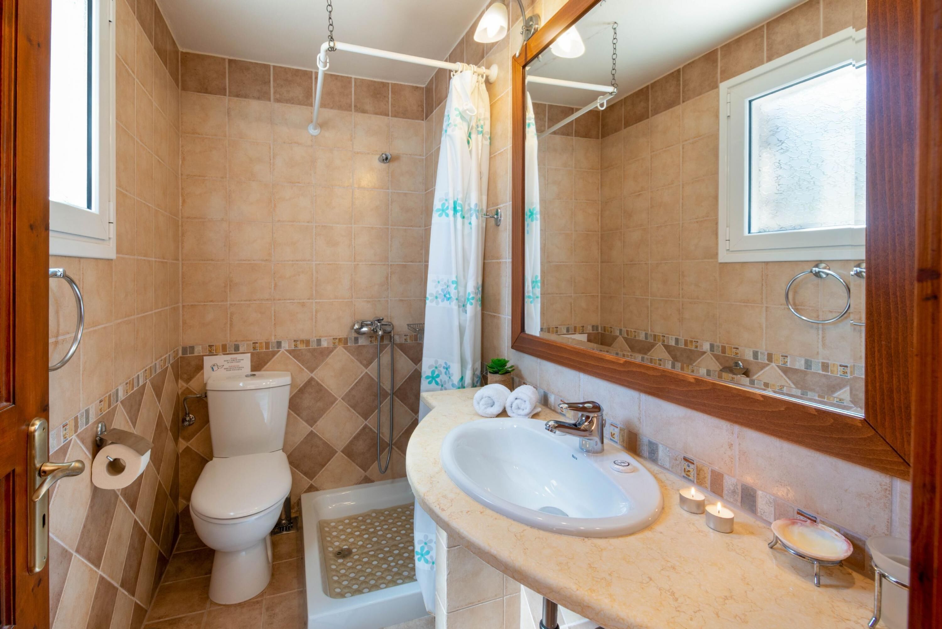 Une salle de bain équipée de toilettes, d’un lavabo, d’une douche et d’une fenêtre.