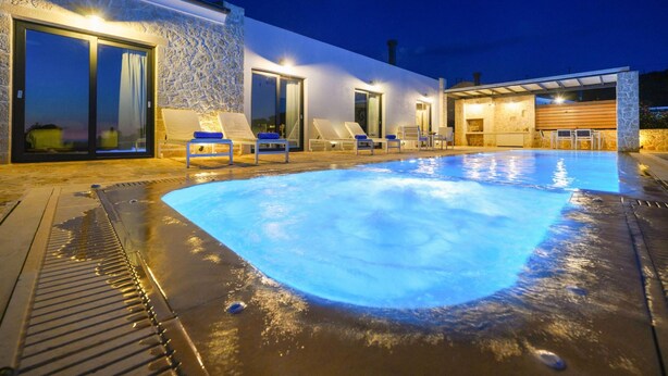A swimming pool with lounge chairs and a stone wall. - Lithari Tria in Agios Georgios (Corfu)