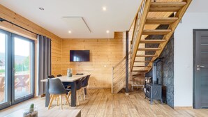 Un interior moderno con una zona de comedor de madera, una escalera y una chimenea de piedra.