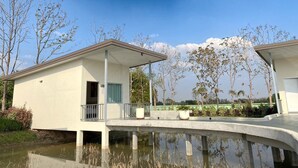 A modern building with a flat roof, a balcony, and a water feature in front. - at Pream and Chan resort (Buriram)