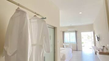 Una habitación de hotel moderna con una cama grande, una zona de estar con sofá y mesa, y un baño con espejo y lavamanos.