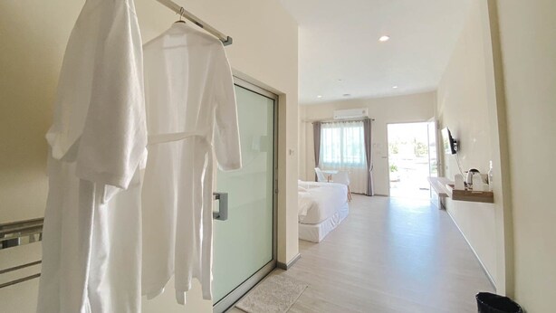 A hotel room with a bed, a sitting area with a chair and table, and a bathroom with a sink and mirror. - at Pream and Chan resort (Buriram)