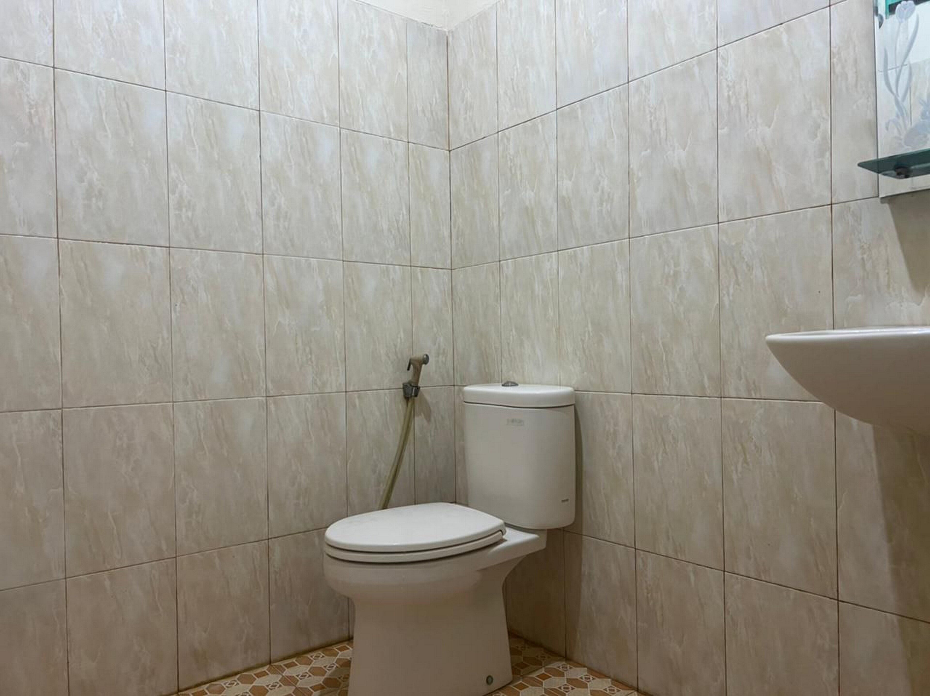 A small, tiled bathroom with a toilet, a shower, and a sink.