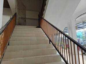 Una escalera con baldosas blancas y barandilla de madera que conduce a un piso superior.