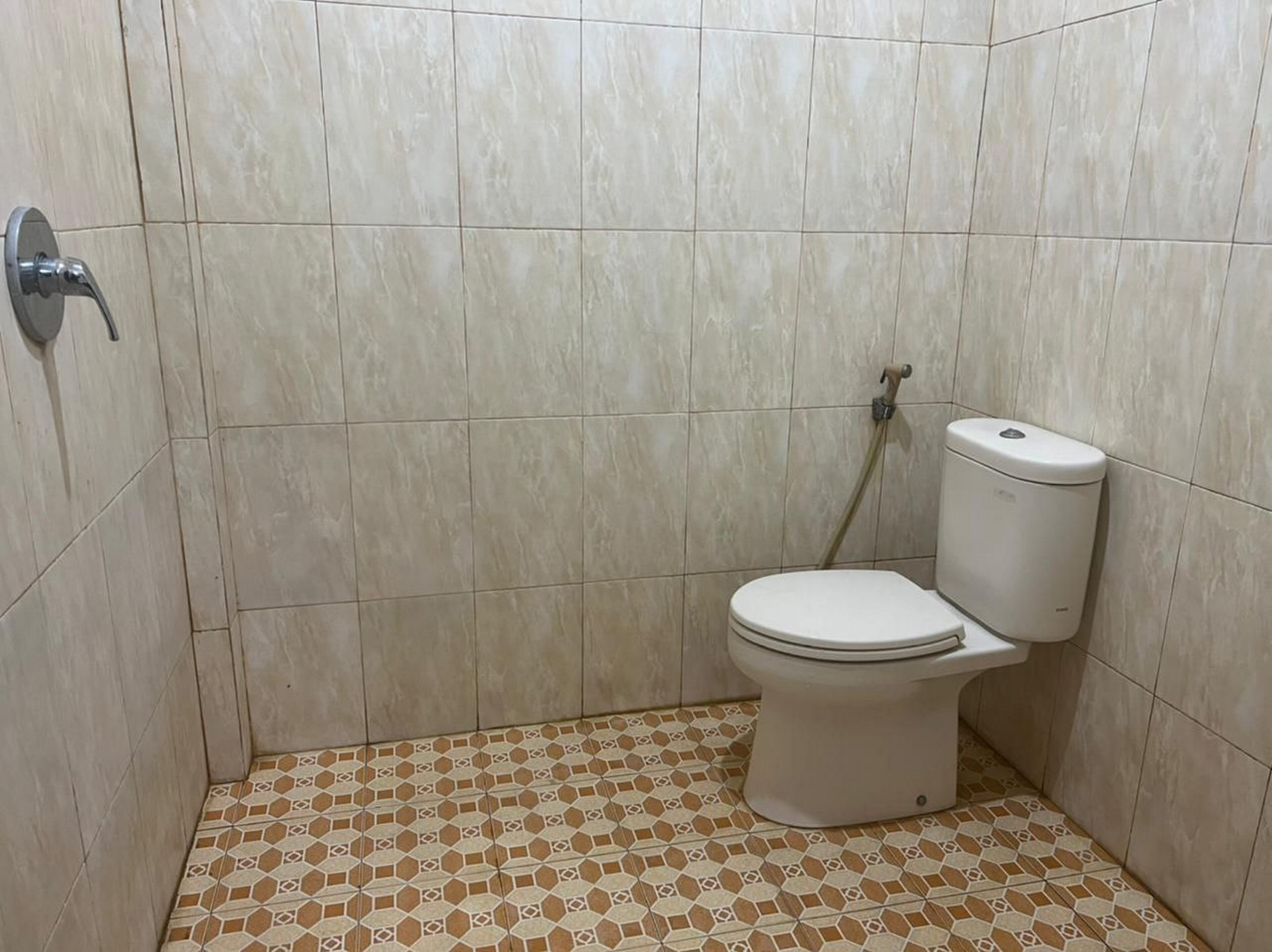 Een kleine badkamer met toilet, douche en betegelde wanden en vloer.